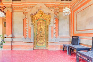 An ornate temple entrance with a detailed golden door, a bench, and a hanging light fixture. - Hotel O Ubud Asri Homestay Near Monkey Forest (Ubud)
