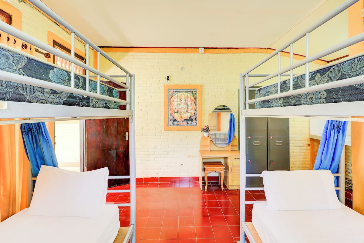 Una habitación de residencia estudiantil con camas literas, un escritorio, una silla y un armario.