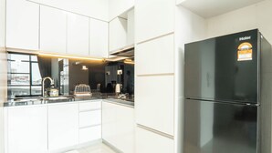 Una cocina moderna con armarios blancos, un refrigerador negro y encimeras de acero inoxidable.