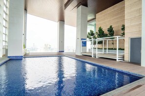 A modern indoor swimming pool with clear blue water, surrounded by wooden flooring and white railings. - Azure Residences Kelana Jaya by Airhost (Petaling Jaya)