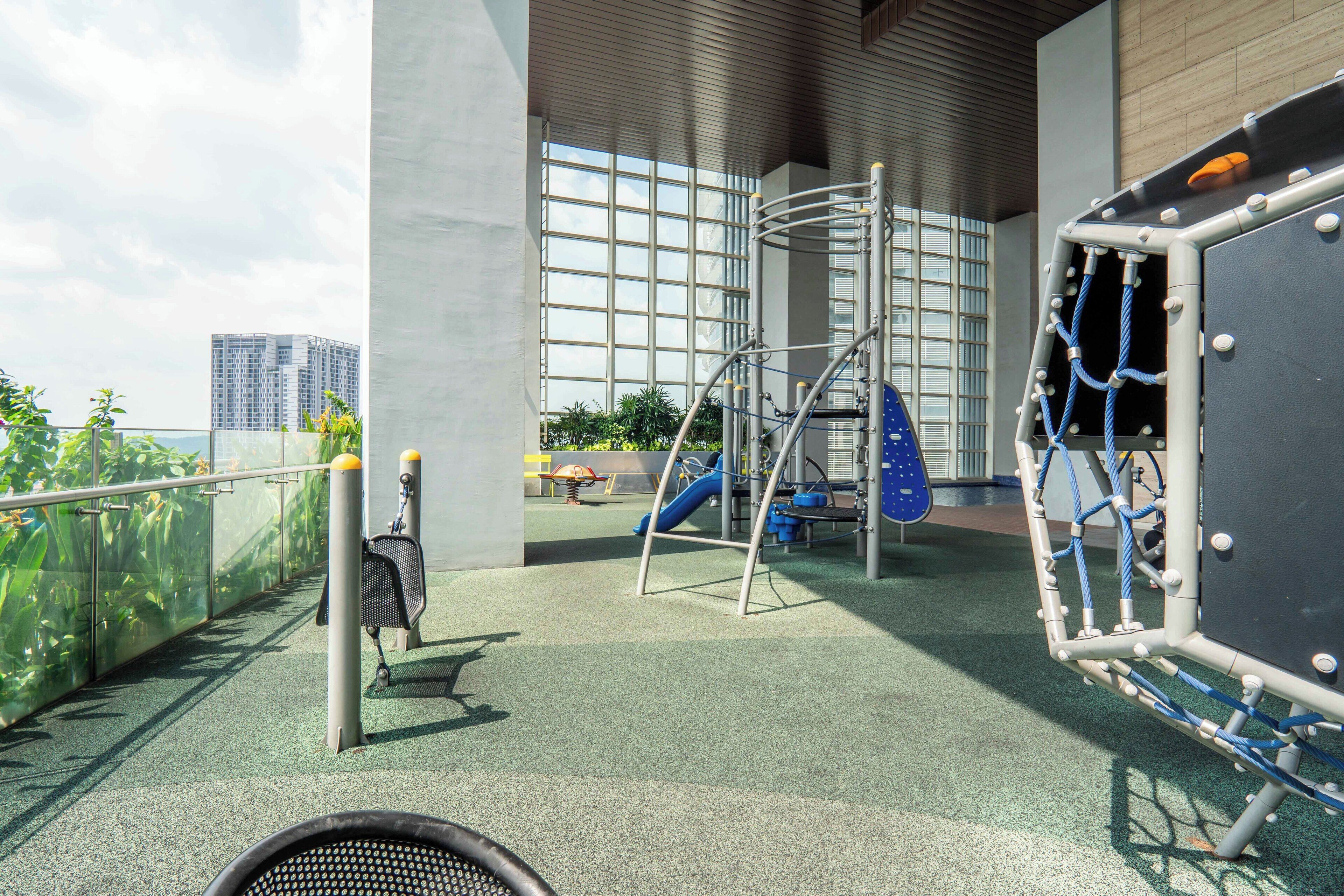 An outdoor play area with a climbing structure, slides, and a fenced garden.