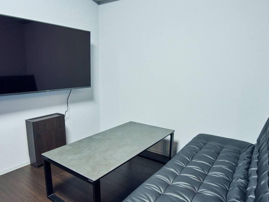 Una sala de estar moderna con un televisor de pantalla plana montado en la pared, una mesita y un sofá gris.