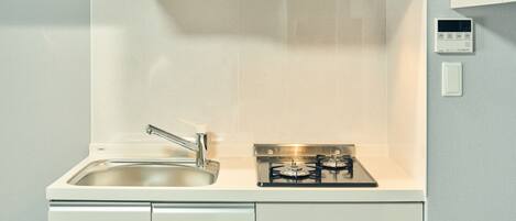 A compact kitchen with a stainless steel sink, a gas stove, and a built-in oven.