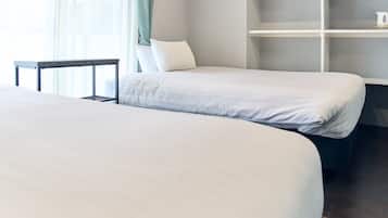 Een hotelkamer met twee bedden, een tafeltje en een inbouwkast.