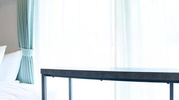 A room with a bed, a table, and a window with curtains.