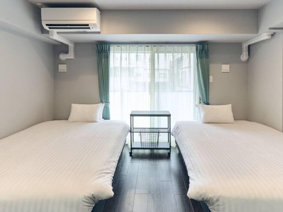 Ein Hotelzimmer mit zwei Betten, einem kleinen Tisch und einem Fenster mit Vorhängen.