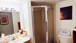 A bathroom with a shower, toilet, sink, and mirror.
