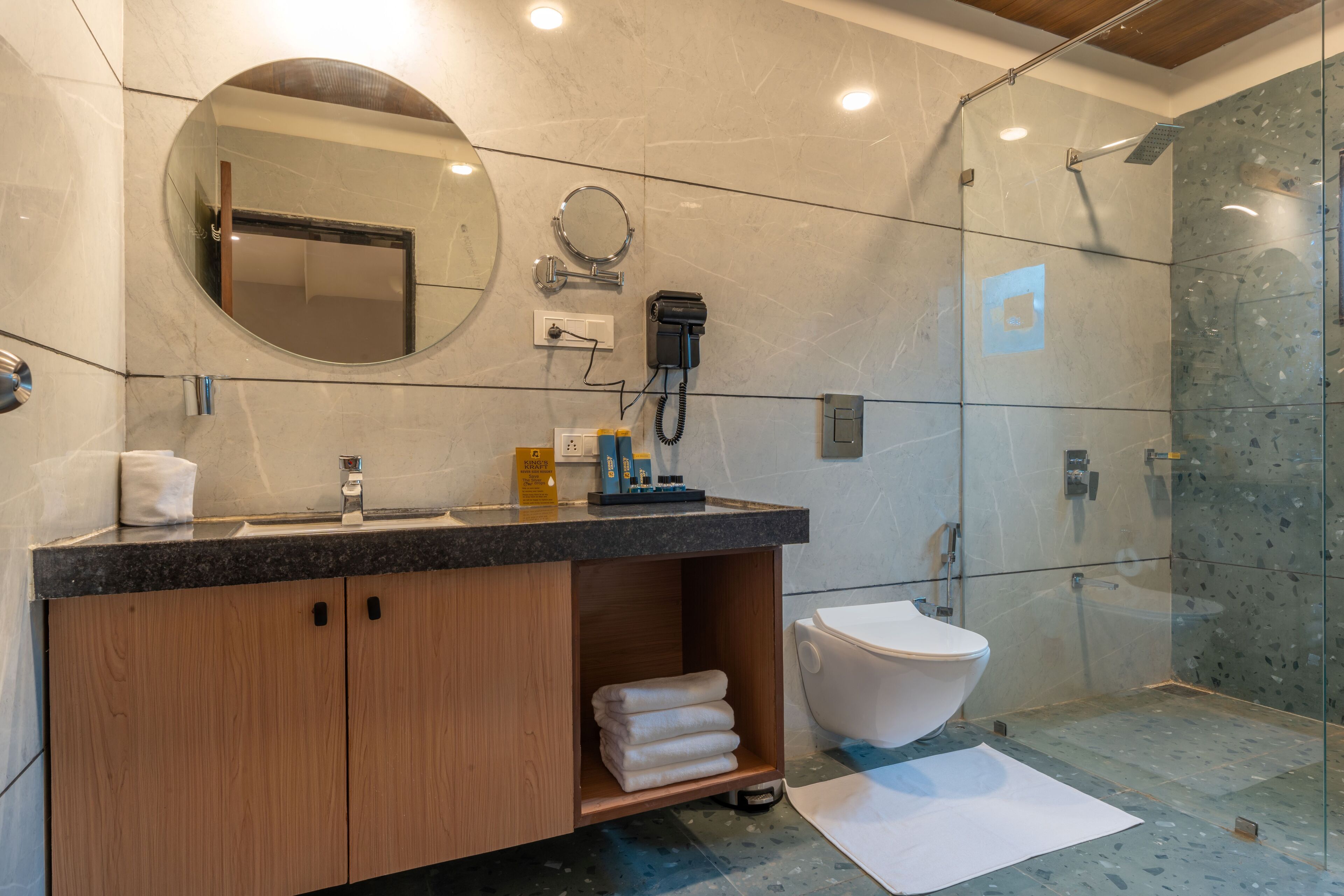 A modern bathroom with a marble vanity, a toilet, and a glass-enclosed shower.