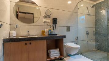 A modern bathroom with a marble vanity, a toilet, and a glass-enclosed shower.