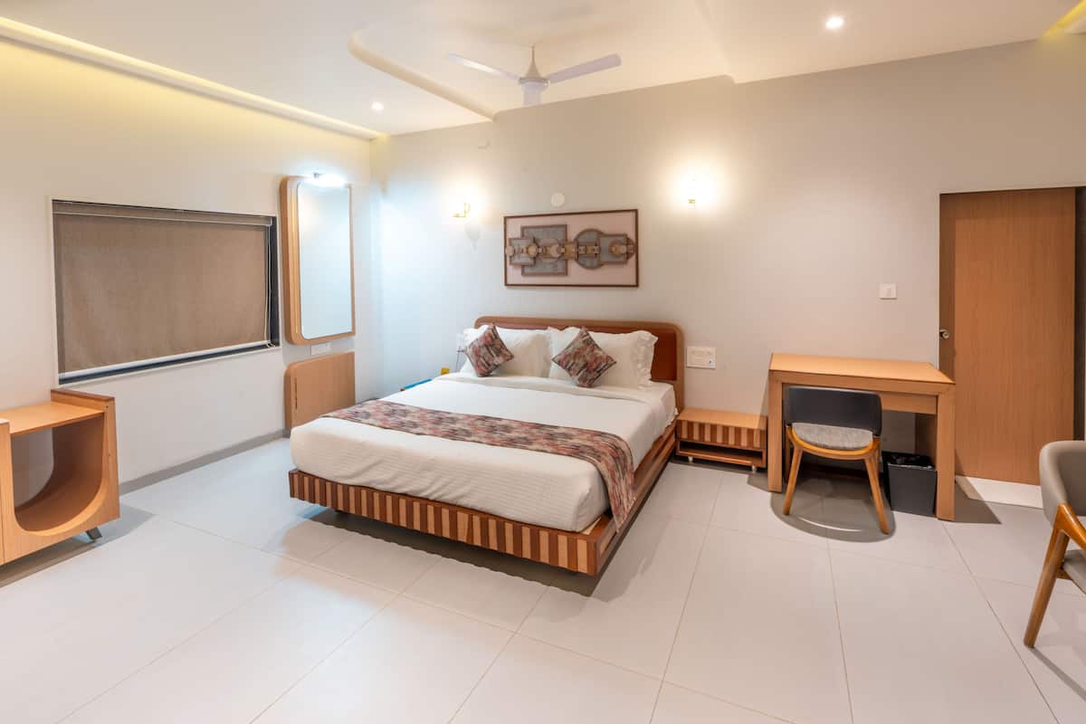 A modern bedroom with a bed, bedside tables, a desk, and a chair.
