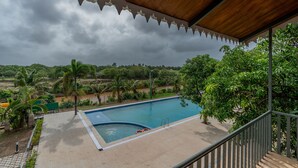 A swimming pool with a wooden deck and a view of the surrounding landscape. - Kings Kraft River Side Resort  (Talala)