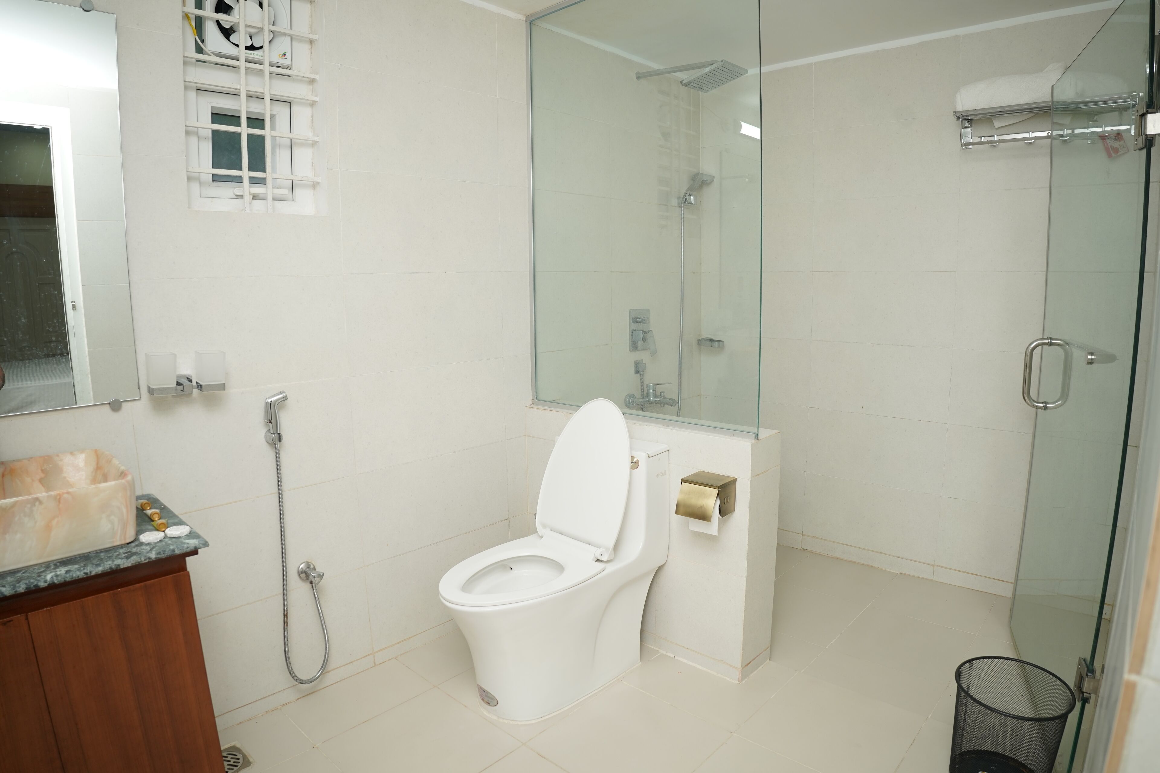 Een moderne badkamer met toilet, douche en een douchecabine met glazen wanden.