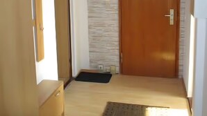 Un pasillo con puerta de madera, pared de piedra y suelo de madera.