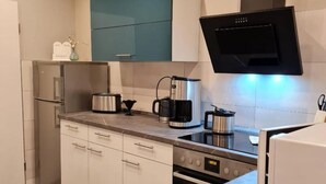 Une cuisine moderne avec des meubles blancs, une hotte noire, des appareils en acier inoxydable et un plan de travail en marbre.