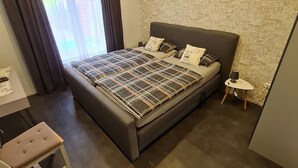 Une chambre moderne avec un grand lit, un petit bureau, une chaise et une lampe.