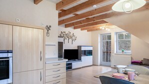 A modern kitchen with wooden cabinets, a built-in oven, and a flat-screen TV.