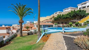 A residential area with a swimming pool, palm trees, and houses with red-tiled roofs. - Ocean View Montesol Apartment with 2-bedrooms and outdoor swimming pool (Costa Adeje)