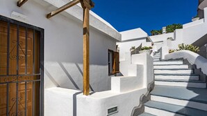 A white-washed building with a wooden door and a staircase leading to a higher level. - Ocean View Montesol Apartment with 2-bedrooms and outdoor swimming pool (Costa Adeje)