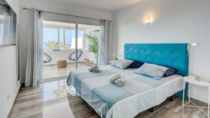 A modern bedroom with a large bed, a blue headboard, and a view of the outdoors. - Ocean View Montesol Apartment with 2-bedrooms and outdoor swimming pool (Costa Adeje)