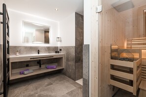A modern bathroom with a wooden vanity, a large mirror, and a sauna area.