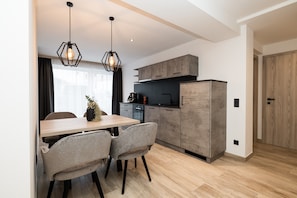 Une cuisine moderne avec des meubles en bois, une table à manger avec des chaises et des luminaires suspendus.