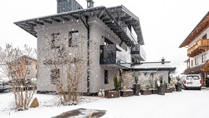 Un bâtiment moderne doté d’un toit en pente, de grandes fenêtres et d’une allée recouverte de neige.