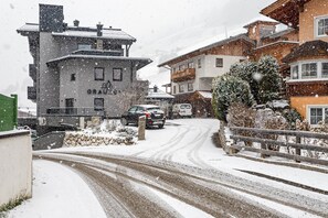 A snow-covered street with buildings, a car, and a truck.