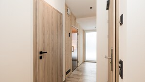 Un couloir avec des portes en bois, un plancher de couleur claire et un luminaire au plafond.