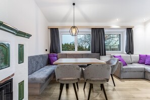 A modern living room with a sofa, chairs, a table, and a window with curtains.