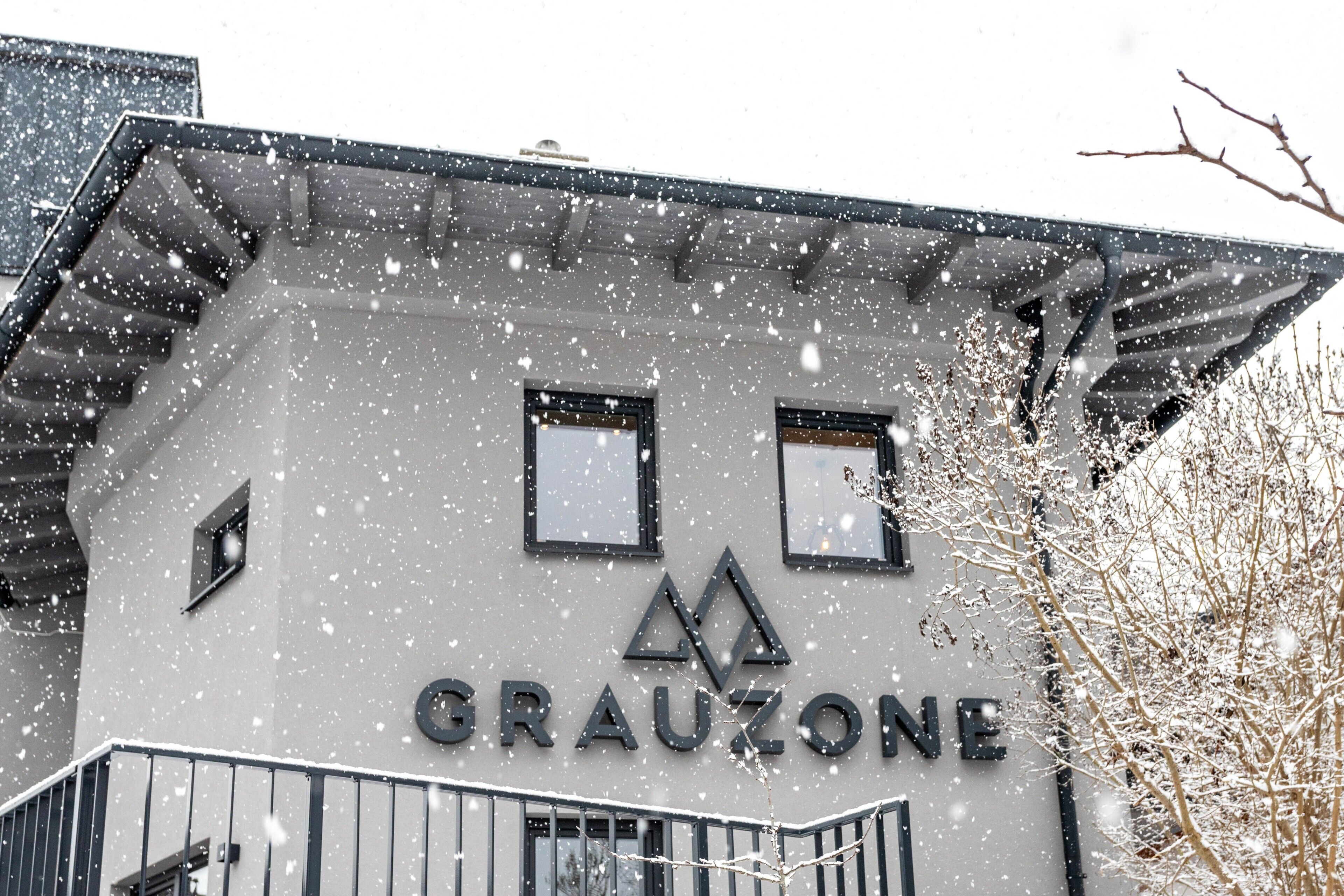 Un edificio con el nombre 'GRAUZONE' en su fachada, de estilo arquitectónico moderno, con un balcón y una escalera.