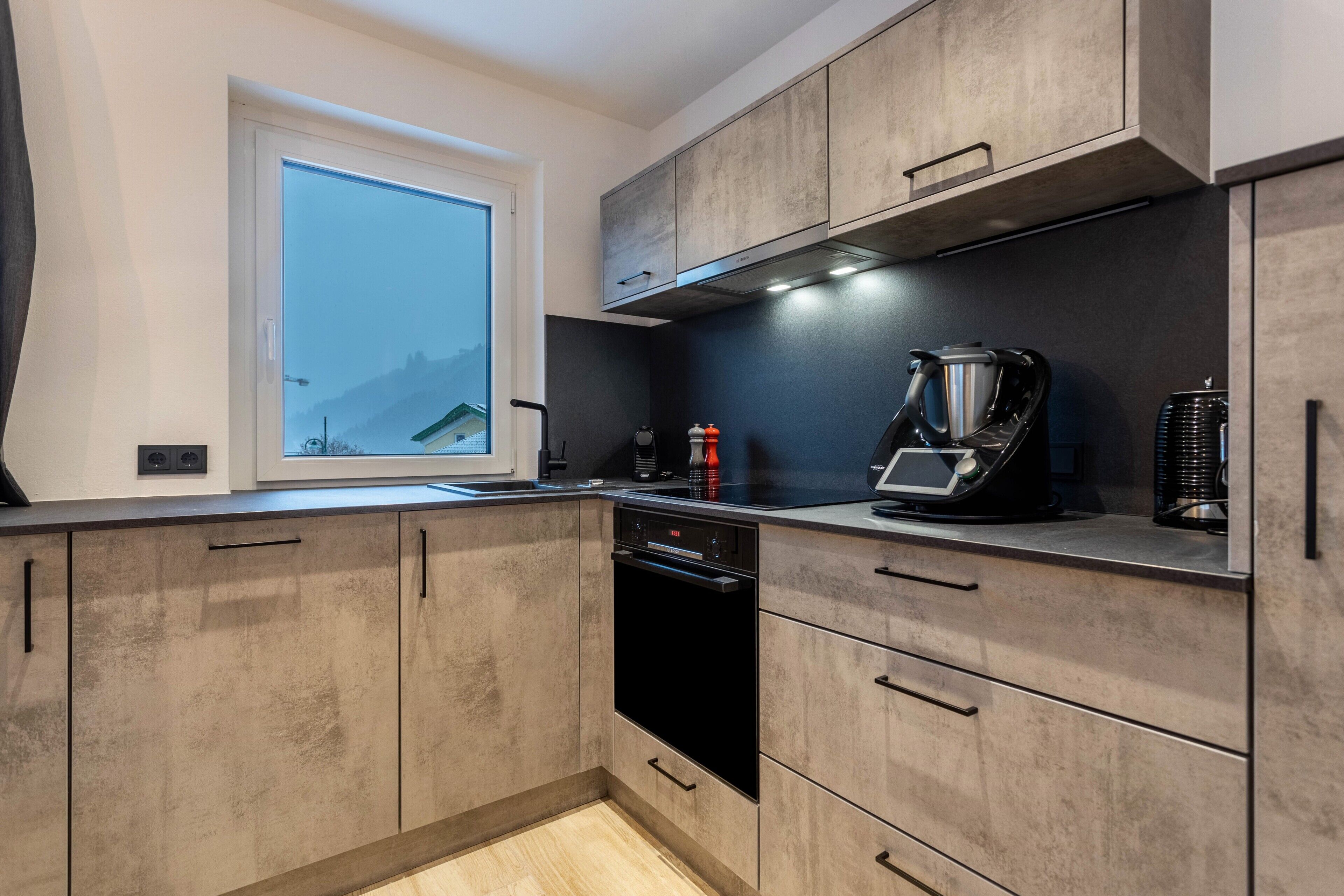 Una cocina moderna con armarios de madera, horno integrado y cafetera.