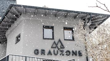A building with the name 'GRAUZONE' on its facade, featuring a modern architectural style with a balcony and a staircase.