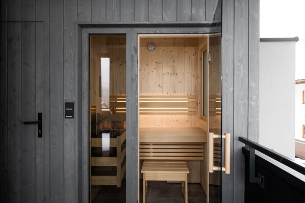 Una sauna con bancos de madera y una puerta que da a una escalera.