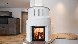 Una chimenea moderna con revestimiento de piedra, un aparador de madera a la izquierda y una pared blanca al fondo.