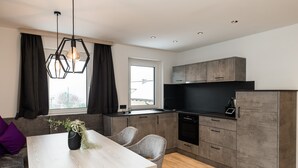Una cocina moderna con armarios grises, un lavavajillas negro y un ventanal con cortinas.