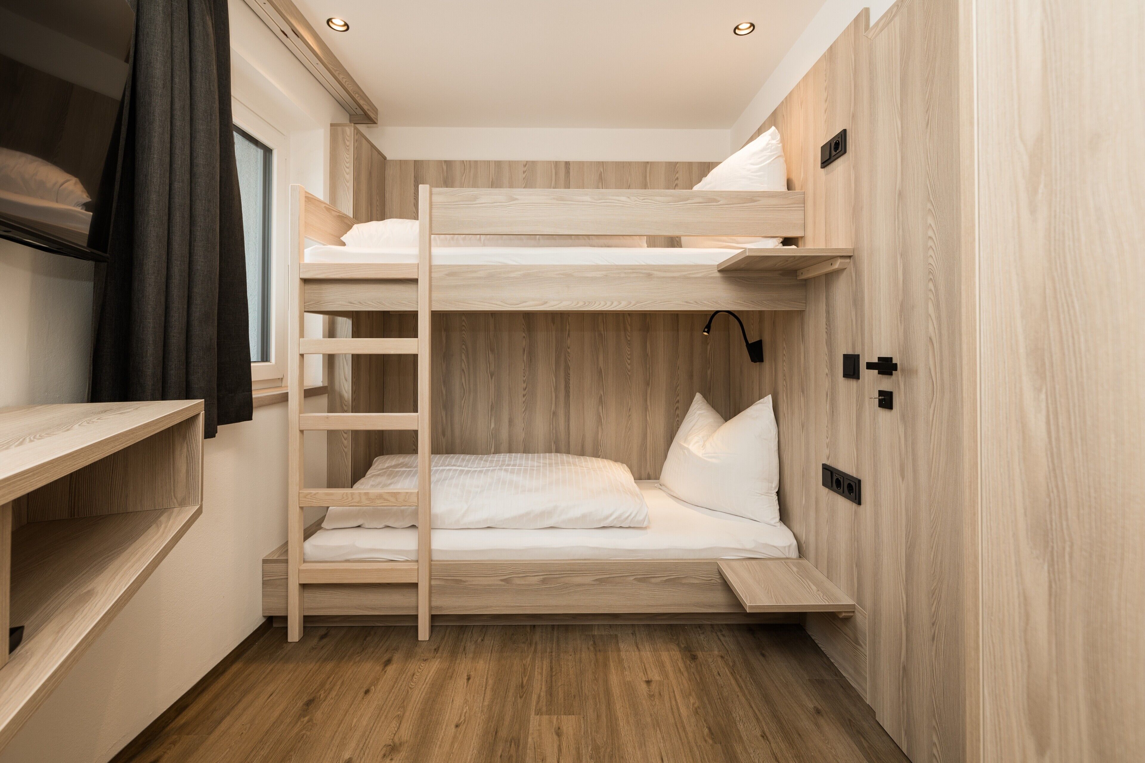 Dormitorio con literas, paredes de madera y ventana.