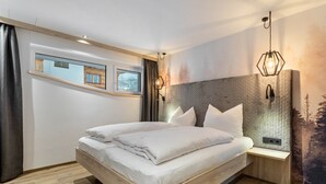 A modern bedroom with a wooden bed, a nightstand, a wall-mounted lamp, and a window with curtains.