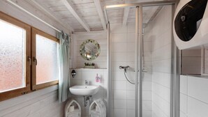 Un baño con cabina de ducha de vidrio, un lavabo blanco y un espejo con marco circular.