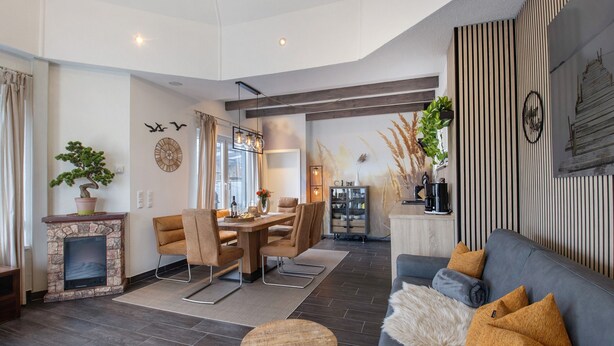 A modern living room with a fireplace, dining area, and a grey sofa with cushions. - Holiday Home Seepanorama - Marina Mücheln with Lake View, Private Terrace & Wi-Fi (Mücheln (Geiseltal))