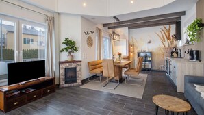 A modern living room with a flat-screen TV, a fireplace, a dining area, and a kitchen. - Holiday Home Seepanorama - Marina Mücheln with Lake View, Private Terrace & Wi-Fi (Mücheln (Geiseltal))