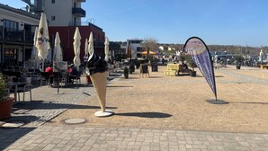 An outdoor seating area with umbrellas, a tall building with a red roof, and a clear sky. - Holiday Home Seepanorama - Marina Mücheln with Lake View, Private Terrace & Wi-Fi (Mücheln (Geiseltal))