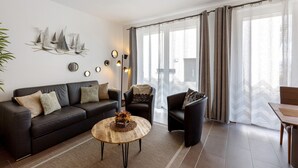 Un salon moderne comprenant un canapé, des fauteuils, une table basse et un élément décoratif mural.