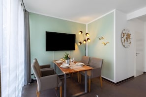 Un coin repas avec une table dressée pour quatre personnes, un téléviseur à écran plat fixé au mur et un élément décoratif mural.