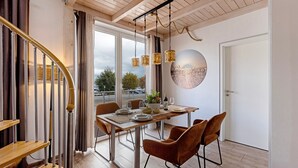 A dining area with a table set for four, a staircase, and a large window with a view. - Holiday Apartment 'Seeschwalbe - Marina Mücheln' with Lake View, Wi-Fi & Air Conditioning (Mücheln (Geiseltal))
