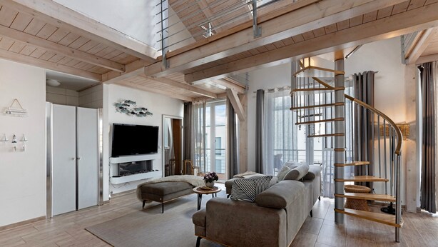 A spacious living area with a modern staircase, a flat-screen TV, and a comfortable seating arrangement. - Holiday Apartment 'Seeschwalbe - Marina Mücheln' with Lake View, Wi-Fi & Air Conditioning (Mücheln (Geiseltal))