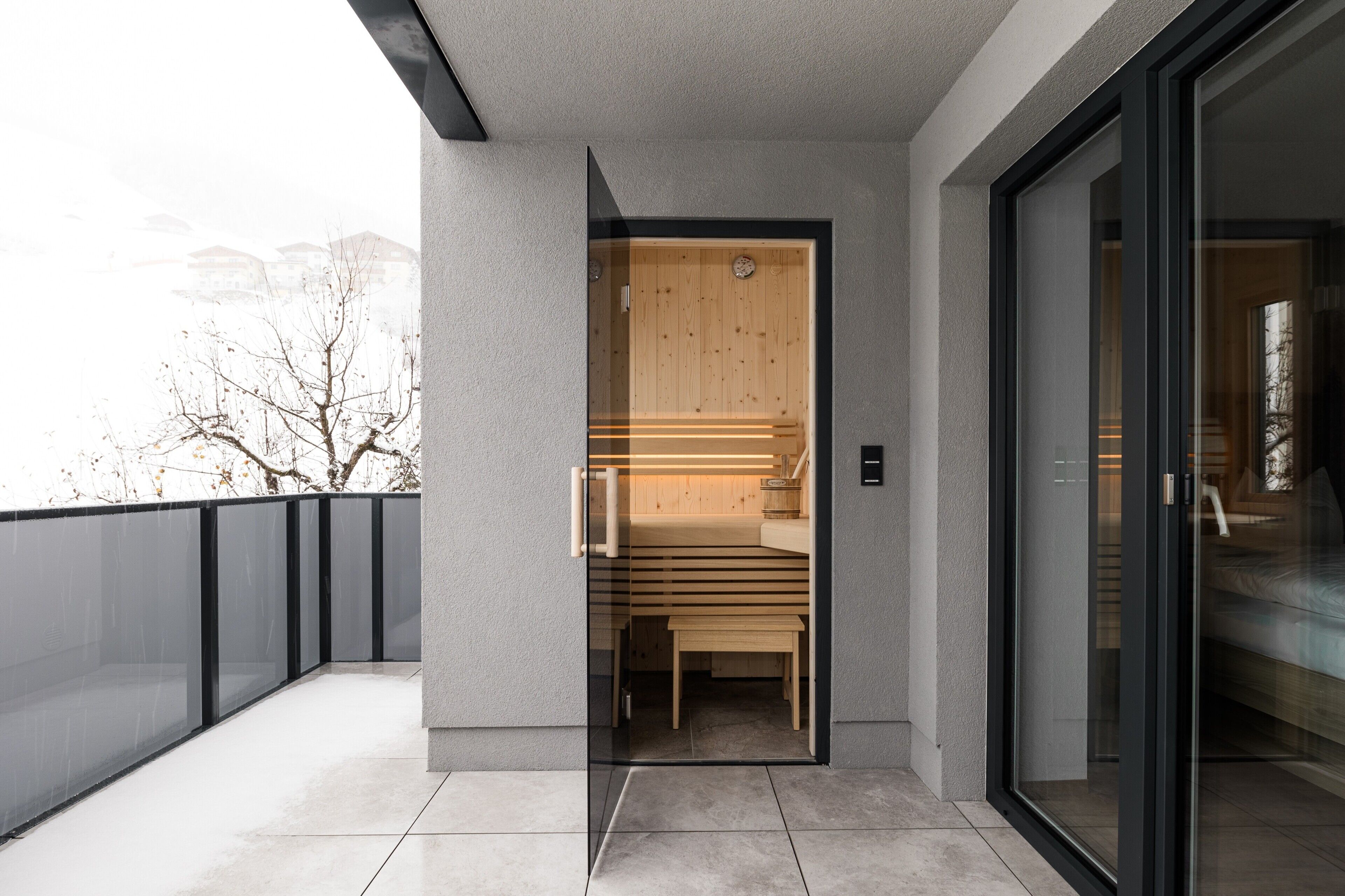 Un edificio moderno con puerta de vidrio que da a una habitación con un banco de madera y una pequeña mesa.