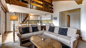 Una sala de estar moderna con un sofá modular, una mesa de centro y una escalera con vigas de madera.