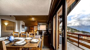 Comedor con una mesa de madera dispuesta para cuatro, una jarra azul y una chimenea.