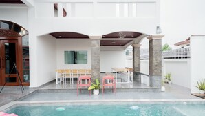A modern outdoor pool area with a dining setup and a staircase leading to an upper level. - The Star Pool Villa Hatyai (Hat Yai)
