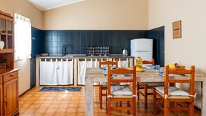 A compact kitchen with a dining area, featuring a tiled backsplash, a refrigerator, and a wooden table with chairs. - Beautiful private villa for 4 guests with TV, balcony, pets allowed and panoramic view (Diano San Pietro)